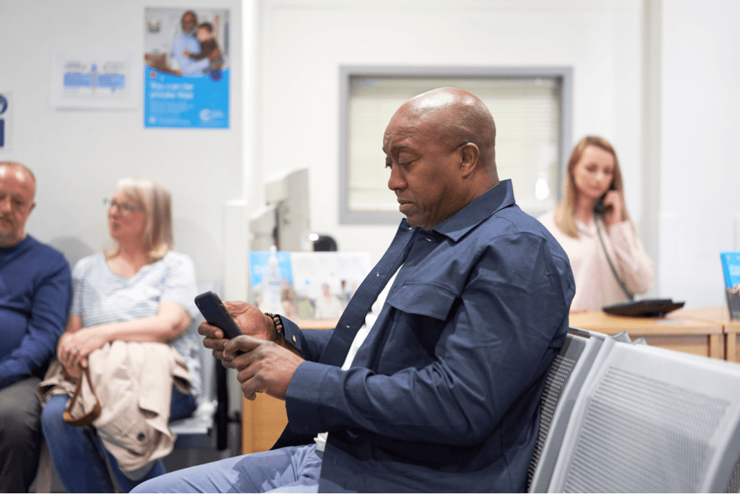 Patient in a waiting room looking at a phone